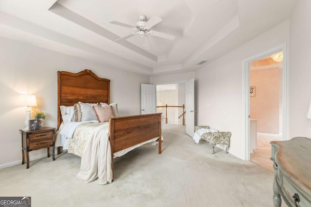 carpeted bedroom with a raised ceiling and ceiling fan