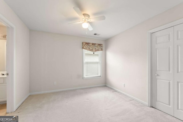 unfurnished bedroom with light carpet, a closet, and ceiling fan