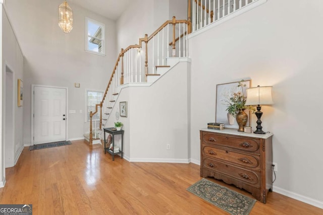 entryway featuring a towering ceiling and light hardwood / wood-style flooring