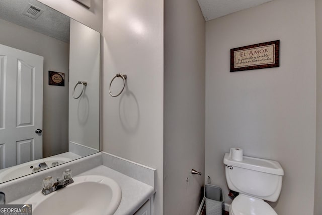 bathroom with vanity, toilet, and a textured ceiling