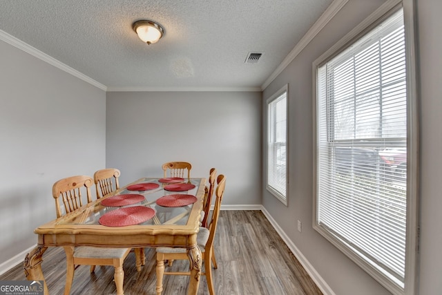 dining room with ornamental molding, hardwood / wood-style floors, and a textured ceiling