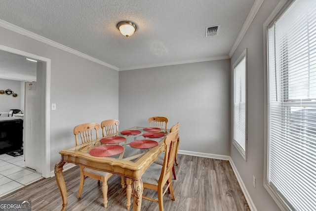 dining area featuring crown molding, light hardwood / wood-style floors, and a textured ceiling