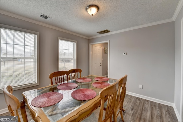 dining area featuring dark wood-type flooring, crown molding, a textured ceiling, and a wealth of natural light