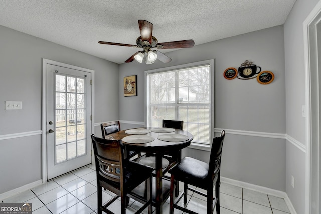 dining room with light tile patterned floors, a textured ceiling, and a healthy amount of sunlight