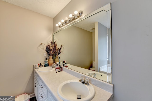 bathroom with vanity, a textured ceiling, and toilet