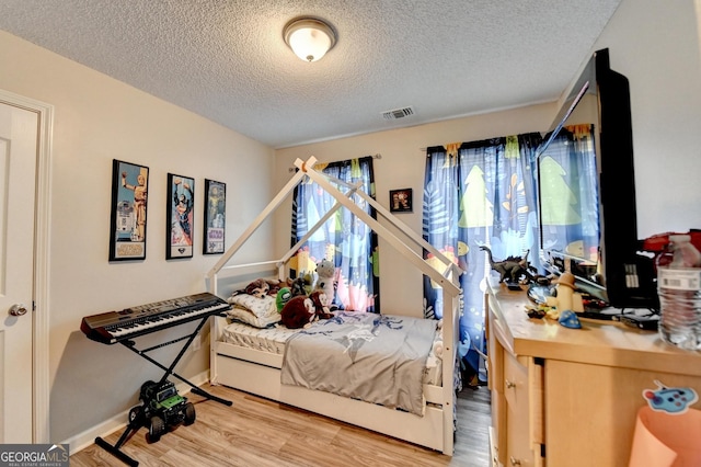 bedroom featuring light hardwood / wood-style floors and a textured ceiling