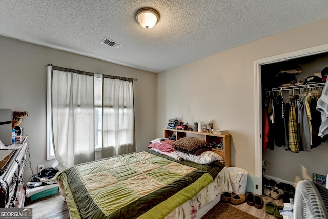 bedroom featuring hardwood / wood-style floors, a closet, and a textured ceiling