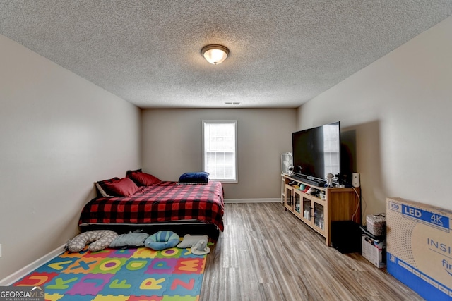 bedroom with hardwood / wood-style floors and a textured ceiling