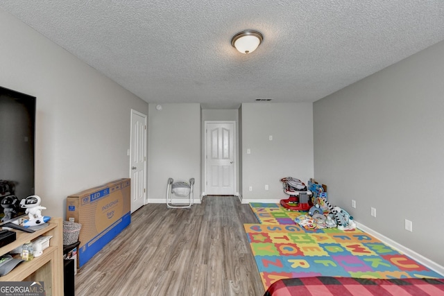 game room with wood-type flooring and a textured ceiling