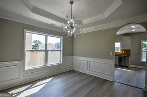 unfurnished dining area with ornamental molding, a healthy amount of sunlight, dark hardwood / wood-style floors, and a tray ceiling