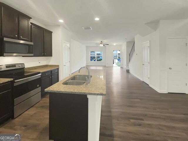 kitchen with sink, ceiling fan, stainless steel appliances, dark hardwood / wood-style floors, and a center island with sink