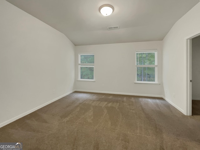 carpeted empty room with vaulted ceiling