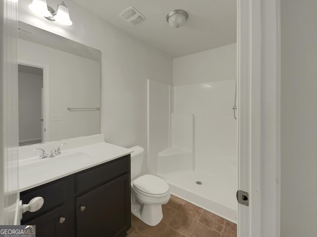 bathroom featuring vanity, toilet, tile patterned flooring, and a shower