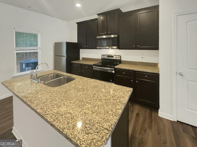 kitchen with sink, light stone countertops, an island with sink, and appliances with stainless steel finishes