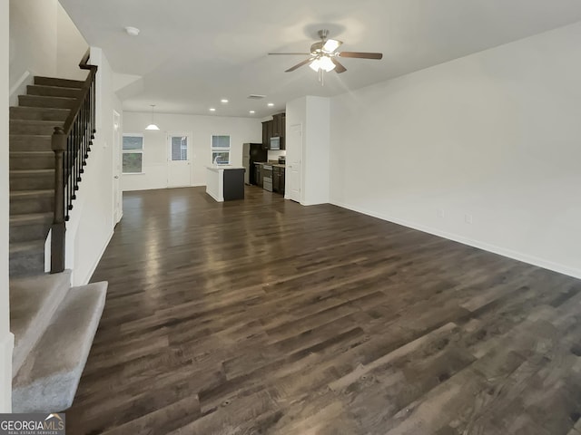 unfurnished living room featuring dark wood-type flooring and ceiling fan