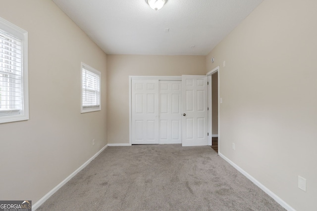 unfurnished bedroom featuring light carpet and a closet