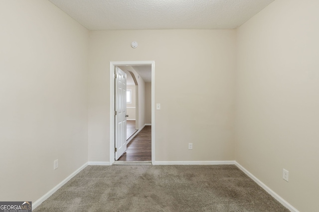 carpeted empty room featuring a textured ceiling