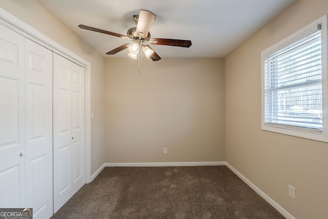 unfurnished bedroom with dark carpet, a closet, and ceiling fan