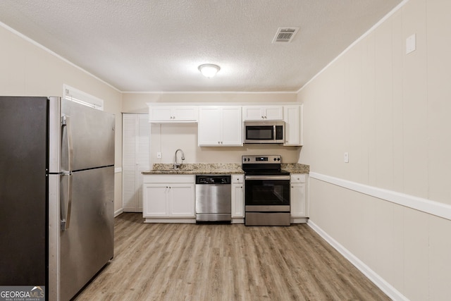 kitchen with sink, white cabinetry, a textured ceiling, appliances with stainless steel finishes, and light hardwood / wood-style floors