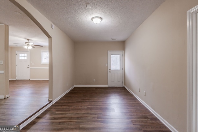 interior space with dark wood-type flooring, a wealth of natural light, and ceiling fan