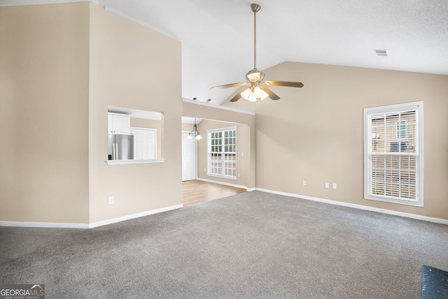 unfurnished living room with ceiling fan, vaulted ceiling, and light carpet