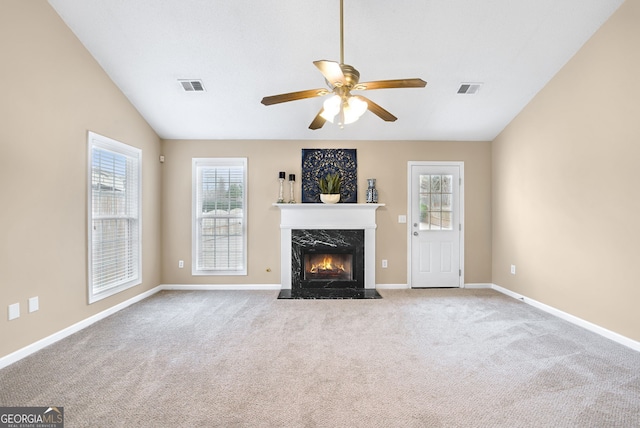 unfurnished living room with vaulted ceiling, light colored carpet, ceiling fan, and a fireplace