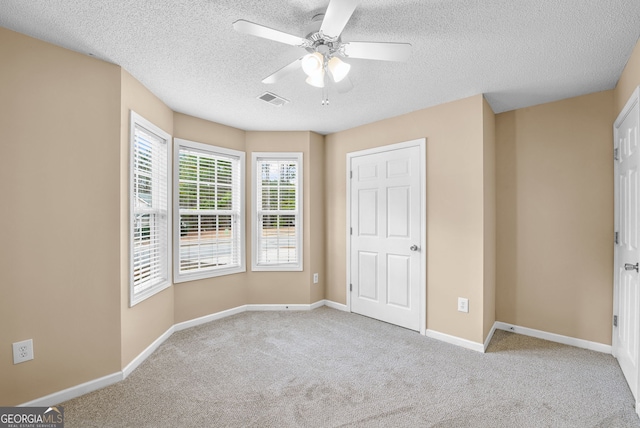 unfurnished bedroom featuring ceiling fan, light carpet, and a textured ceiling