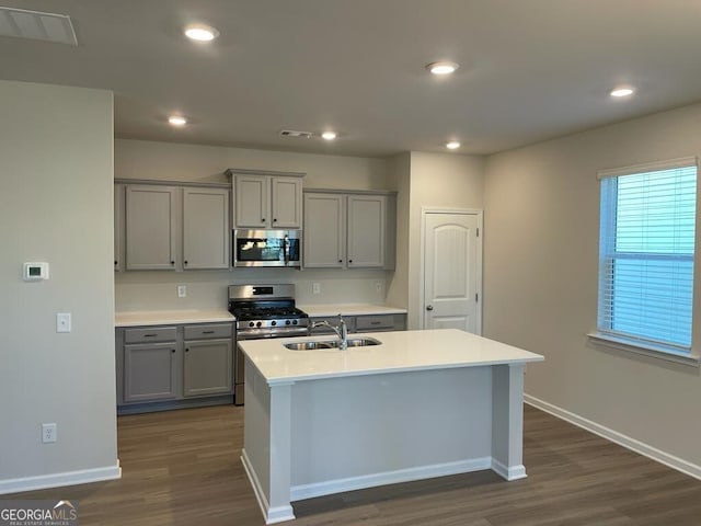 kitchen featuring a center island with sink, appliances with stainless steel finishes, dark hardwood / wood-style floors, and gray cabinetry