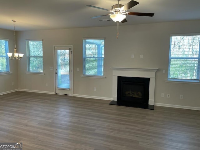 unfurnished living room with a fireplace with raised hearth, wood finished floors, visible vents, and baseboards