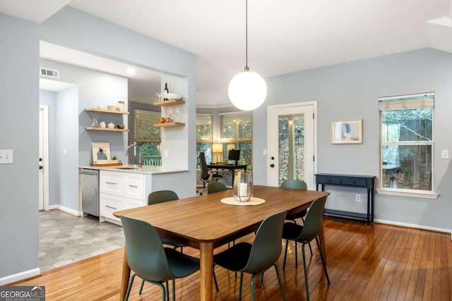 dining room featuring sink, vaulted ceiling, hardwood / wood-style floors, and a wealth of natural light