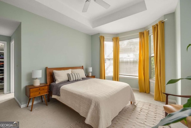 bedroom featuring light colored carpet, ceiling fan, and a tray ceiling