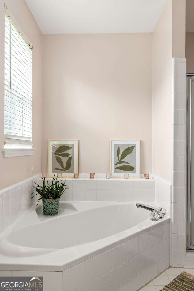 bathroom with a relaxing tiled tub and tile patterned floors