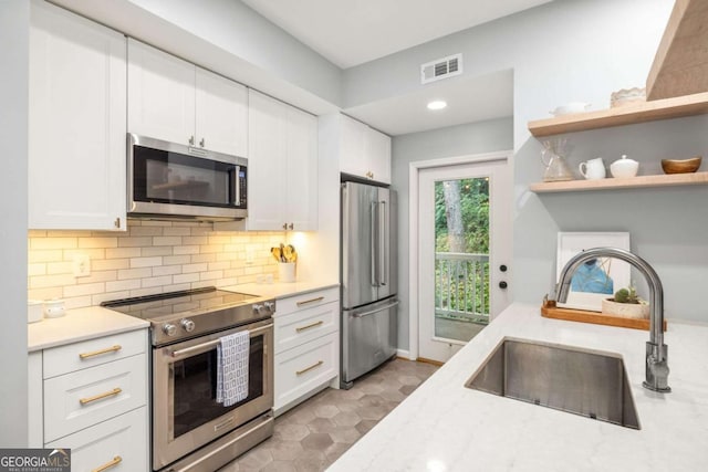 kitchen featuring sink, white cabinetry, tasteful backsplash, stainless steel appliances, and light stone countertops