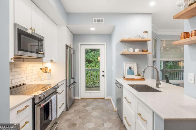 kitchen with sink, white cabinetry, high quality appliances, light stone counters, and decorative backsplash