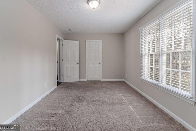 unfurnished bedroom featuring carpet floors, multiple windows, and a textured ceiling