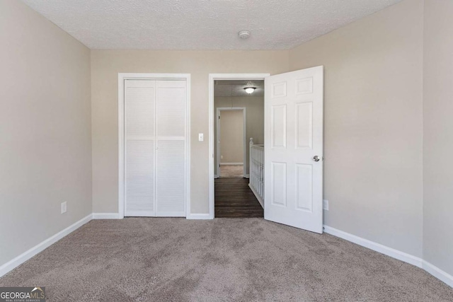 unfurnished bedroom with a closet, a textured ceiling, and carpet flooring