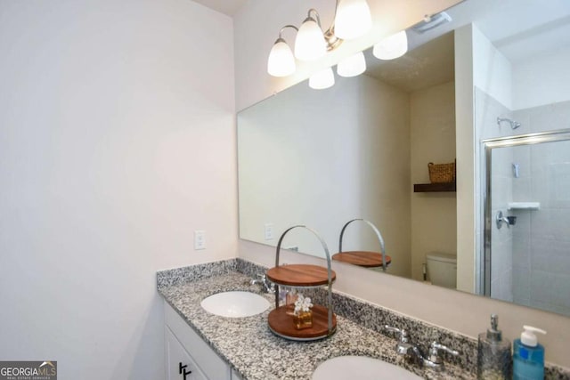 bathroom with vanity, a shower with shower door, and toilet