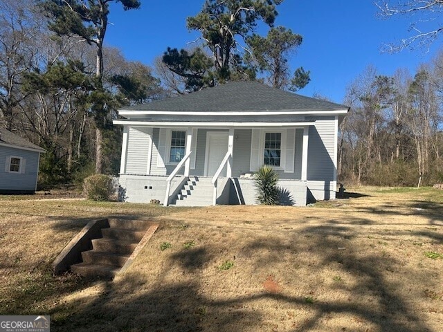 bungalow with covered porch and a front lawn