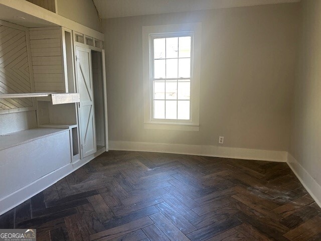 spare room featuring lofted ceiling and dark parquet floors