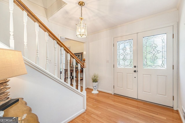 entrance foyer with wood-type flooring, crown molding, and stairs