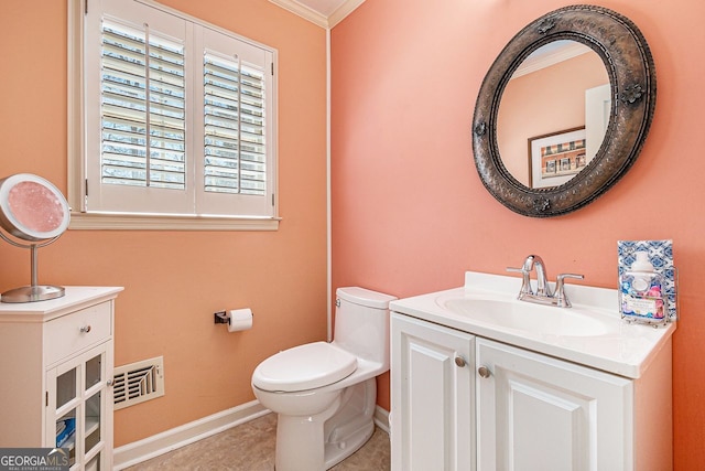 bathroom featuring toilet, vanity, baseboards, visible vents, and crown molding