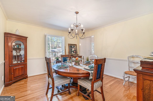 dining room with crown molding, light wood-style flooring, baseboards, and an inviting chandelier