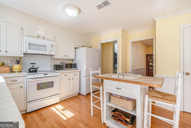 kitchen featuring tile counters, white appliances, visible vents, and a kitchen breakfast bar