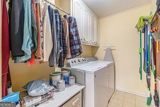 laundry area with light tile patterned floors, baseboards, cabinet space, washing machine and clothes dryer, and crown molding