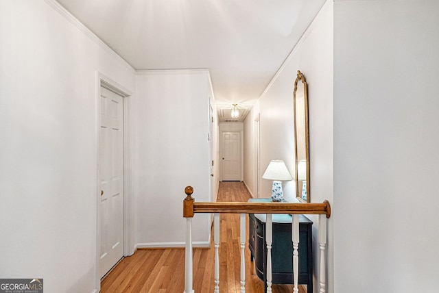 hallway with ornamental molding, light wood finished floors, an upstairs landing, and baseboards