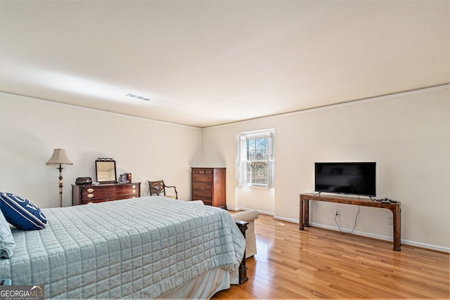 bedroom with light wood finished floors, visible vents, and baseboards