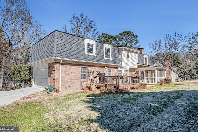 back of property with a garage, a shingled roof, mansard roof, a yard, and brick siding