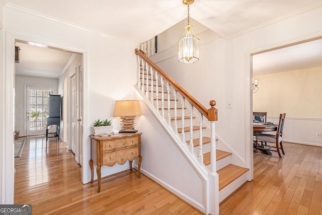 stairway with wood-type flooring, a chandelier, and crown molding