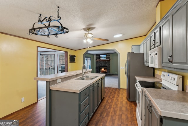 kitchen with gray cabinets, an island with sink, sink, and white appliances