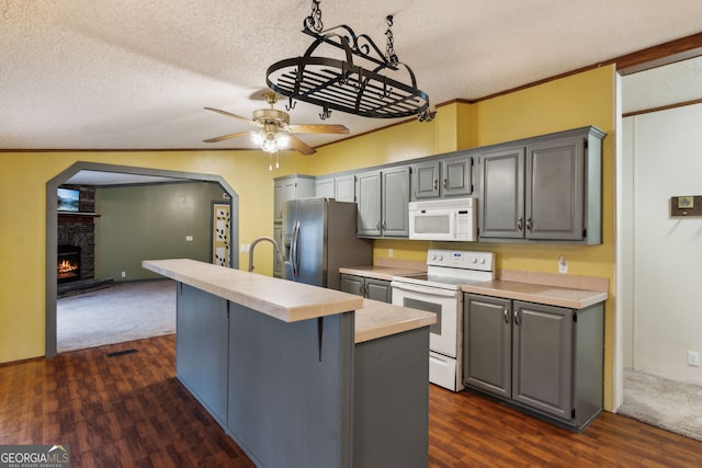 kitchen featuring white appliances, gray cabinets, a kitchen breakfast bar, a fireplace, and ornamental molding